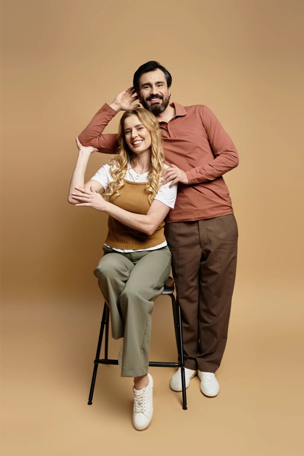 joyful-middle-aged-couple-poses-together-warm-toned-studio-playful-moment